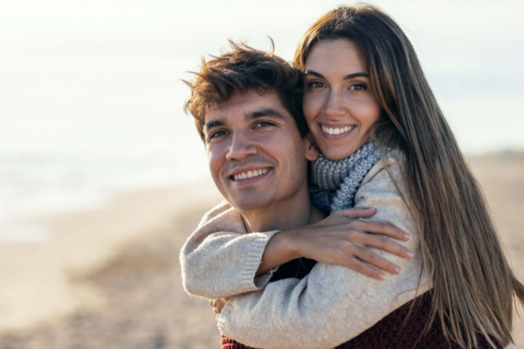 a couple embracing on the beach and smiling at the camera